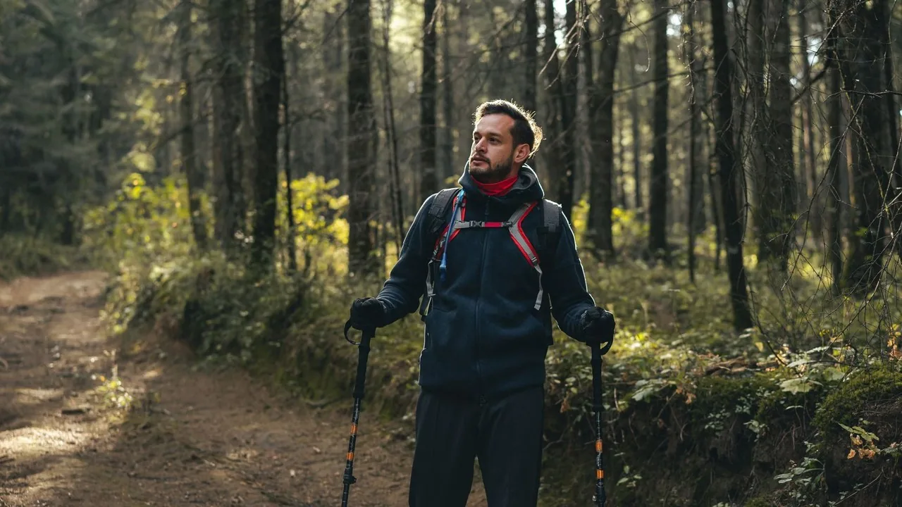 Mężczyzna testuje kije trekkingowe na leśnym szlaku.