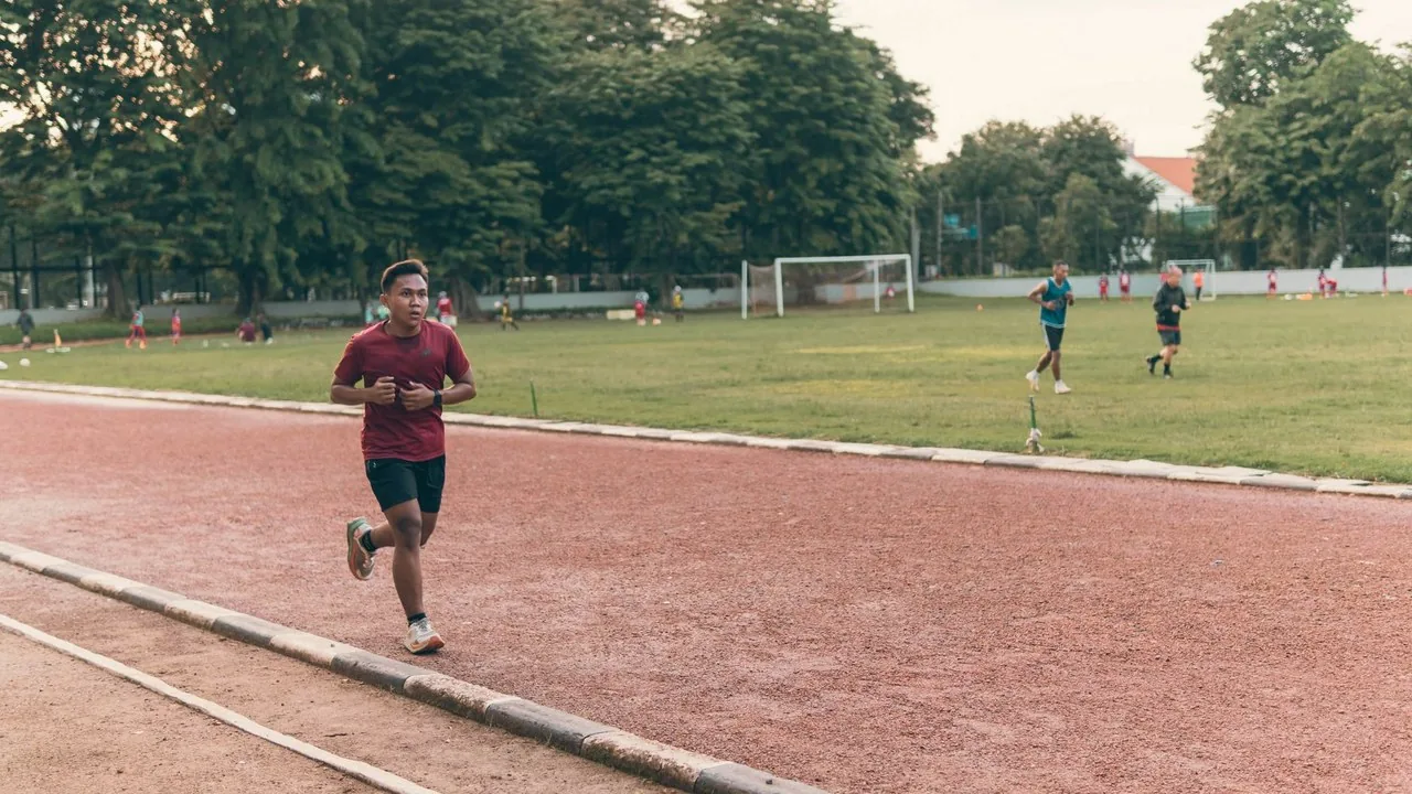 Biegacz trenujący interwały na bieżni o zachodzie słońca